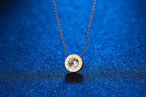 Macro shot of rose gold necklace with Roman numerals and a sparkling center zircon