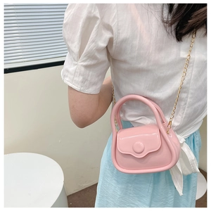 Detailed side view of a mini bright pink jelly bag with a gold metal chain strap on a model
