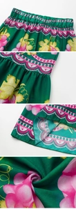 Detail view of green satin skirt featuring floral print and elastic waistband textures