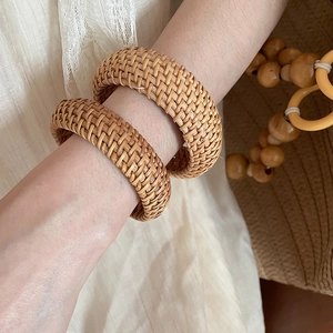 Détail de deux bracelets en rotin tissé faits main de couleur bois naturel