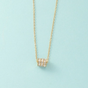 Macro shot of gold-plated cylinder pendant necklace with three rows of clear crystals