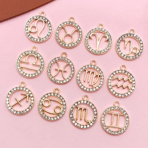 Macro shot of twelve zodiac gold pendants with white rhinestones on a pink background