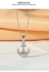 Macro view of stainless steel anchor pendant with white zircon stones on silk fabric