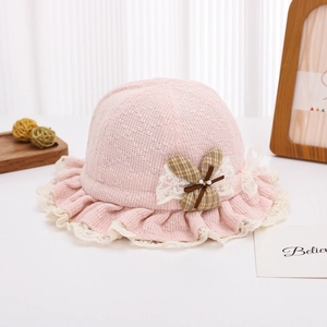 Detail of pink knitted baby hat with lace trim, yellow bow and pearl accents