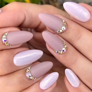 Close-up of matte nude pink and white glitter nails with golden rhinestone crescent detail