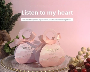 Detailed view of a pink wedding favor box with a satin ribbon and gold 'Thank you' text