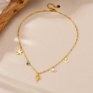 Golden starfish and shell charm necklace with turquoise beads on beach sand
