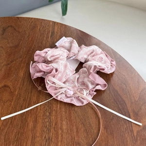 Vintage floral pink scrunchie with silk ribbon bow and heart pendant on wood table