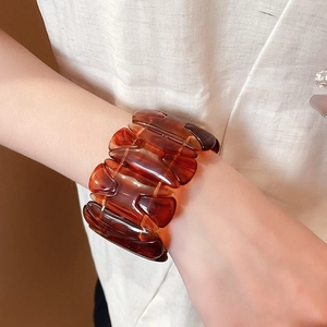 Close-up of amber tortoiseshell wide resin bracelet with geometric links on wrist