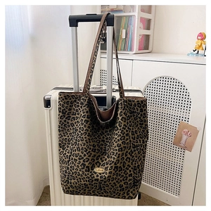Leopard print tote bag hanging on a white suitcase showing large capacity and design