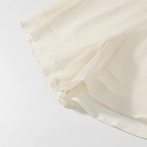 Detail shot of pleated cream chiffon fabric hem with delicate stitching on dress