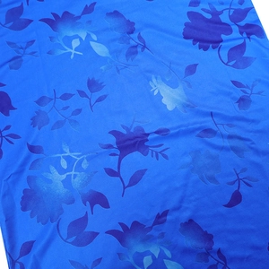 Détail du tissu jacquard bleu avec motifs floraux brillants et texture damassée