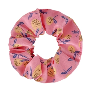 Close-up of pink fabric scrunchie with yellow pineapple and blue leaf pattern prints