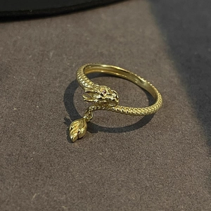 Close-up of golden dragon ring with red eyes, scale texture and leaf charm detail