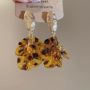 Macro detail of acrylic petal tassel earrings with amber leopard print and gold textured metal
