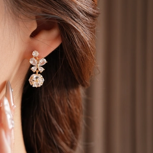 Gros plan de boucles d'oreilles dorées papillon et cube avec cristaux sur mannequin