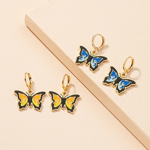 Detail of gothic butterfly earrings featuring vibrant blue and orange flame enamel patterns