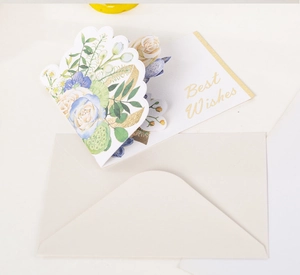 Macro detail of 3D pop-up floral card with blue white roses and gold Best Wishes text