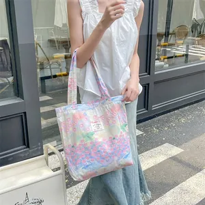 Detailed view of floral canvas tote bag with 'PLAY RABBIT' label and soft pastel patterns