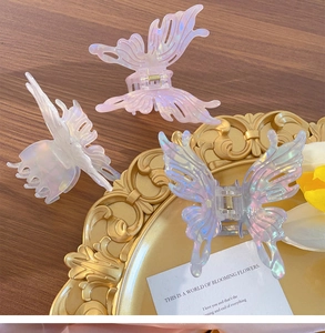 Detailed view of iridescent butterfly hair claws on a gold decorative tray with floral accents