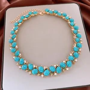 Vintage gold necklace set with blue oval stones and white zircon accents on gray background