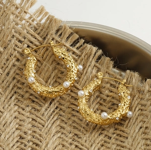 Detail of 18k gold lava texture earrings with pearls and crystals on burlap background
