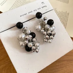 Chic silver needle cluster earrings with black crystal beads and white pearls on a box
