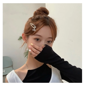Silver safety pin hair clip with LOVE letter charm worn by a stylish model