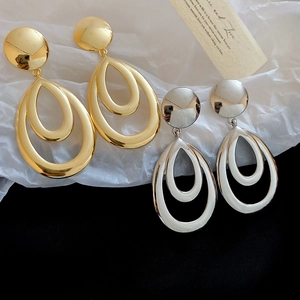 Boucles d'oreilles gouttes évidées polies en or et argent sur fond texturé élégant