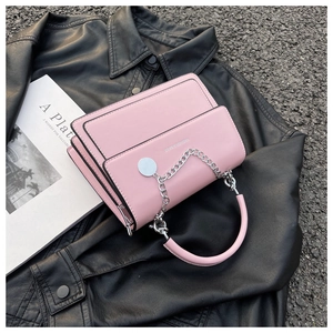 Pink PU leather crossbody bag with silver chain on black jacket and book background