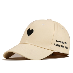 Close-up of beige cotton baseball cap with heart and LOVE HER BUT LEAVE HER WILD embroidery