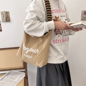 Close-up of khaki canvas tote bag with Bonjour magic print and cat graphic sweatshirt
