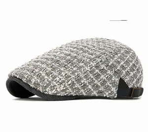 Detail of light gray tweed knit beret cap featuring leather strap and metal adjustment buckle