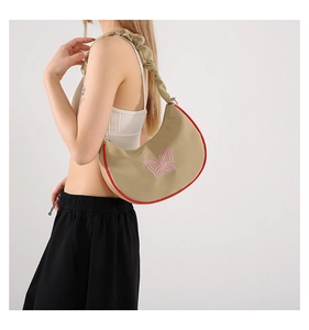 Détail du sac croissant avec broderie papillon rose et bandoulière à volants