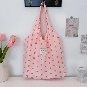 Detailed close-up of a pink tote bag featuring heart patterns and a fabric logo patch