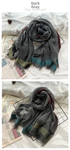 Detailed close-up of dark grey wool scarf with contrasting colored edges and frayed trim