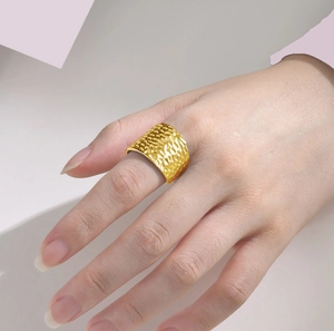 Detail showing a wide 18K gold plated stainless steel ring with hammered texture on finger