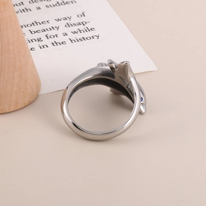 Macro shot of silver dolphin ring with blue eyes on a wooden decorative stand