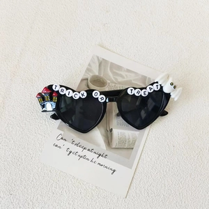 Detail of heart-shaped Halloween sunglasses with Trick or Treat lettering and ghost decor