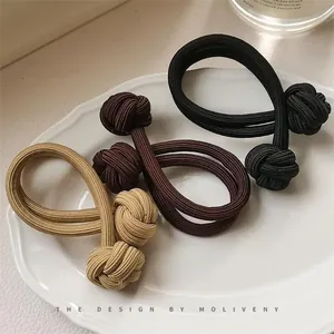 Close-up of three ribbed high-elastic hair ties with Chinese knot design on a ceramic tray