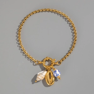 Close-up of golden chain bracelet featuring ceramic blue floral beads and sea shells