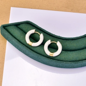 Détail des boucles d'oreilles créoles en émail blanc et plaqué or 18 carats sur présentoir