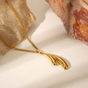 Close-up of golden teardrop pendant on natural stones highlighting metallic luster