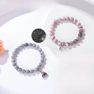 Detailed view of pink and grey zebra stone bracelets with heart projection charms
