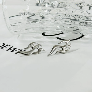 Detailed close-up of silver flame fluid earrings with polished metallic luster finish