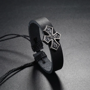 Macro detail of retro cross charm on black braided leather strap with vintage finish