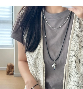 Detail of layered silver dog pendant necklace worn with stylish lace and grey outfit