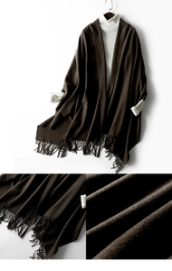 Detail of dark brown knitted shawl with fringe hem and soft wool texture close-up