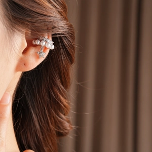 Close-up of silver double-layer ear clips with pearls, crystals and a star pendant
