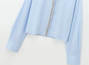Detailed view of light blue poplin shirt with shimmering crystal embellishments on placket